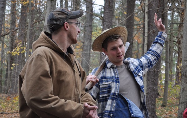 A man in a farmer costume talks to a Fall Harvest visitor