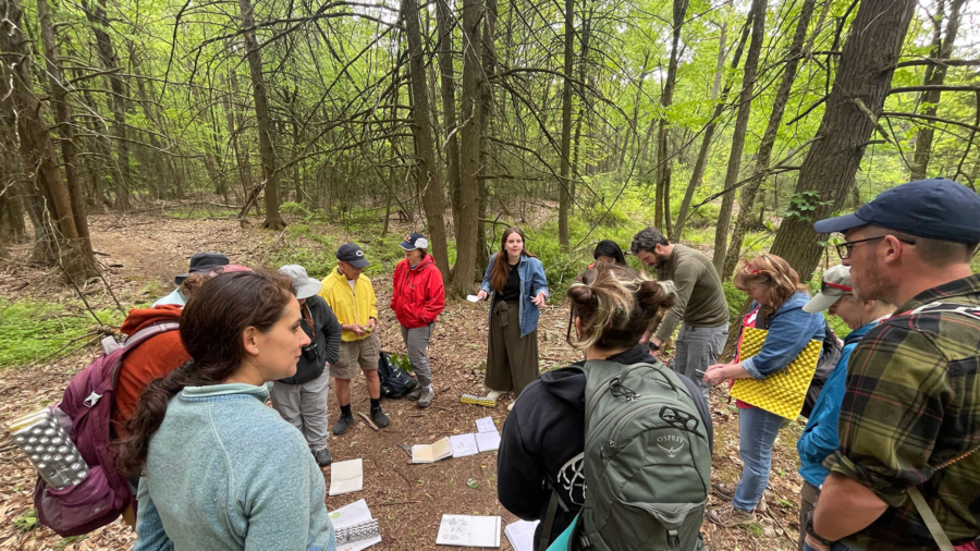 A group of people looking at nature journals outside